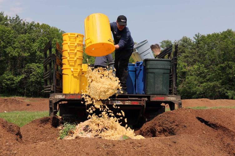 在金曼研究农场，一名UNH餐饮服务工作人员将一个装有面条的黄色水桶倒出来.